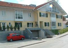 Mehrfamilienhaus in Bad Tölz: Holzfenster mit weißer Oberfläche, grüne Holzfensterläden